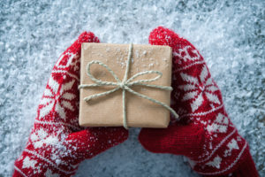 Female hands in winter gloves with christmas gift box